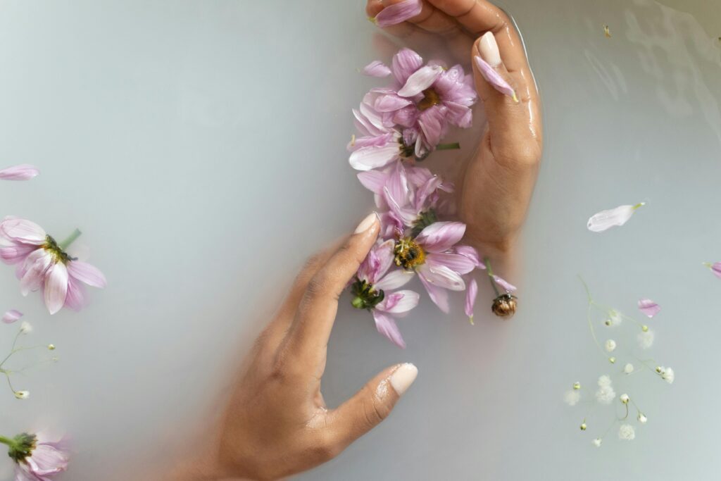 Image pour article sur le blog Serenity Body Mind point com, deux mains dans de l'eau opaque avec des fleurs violettes