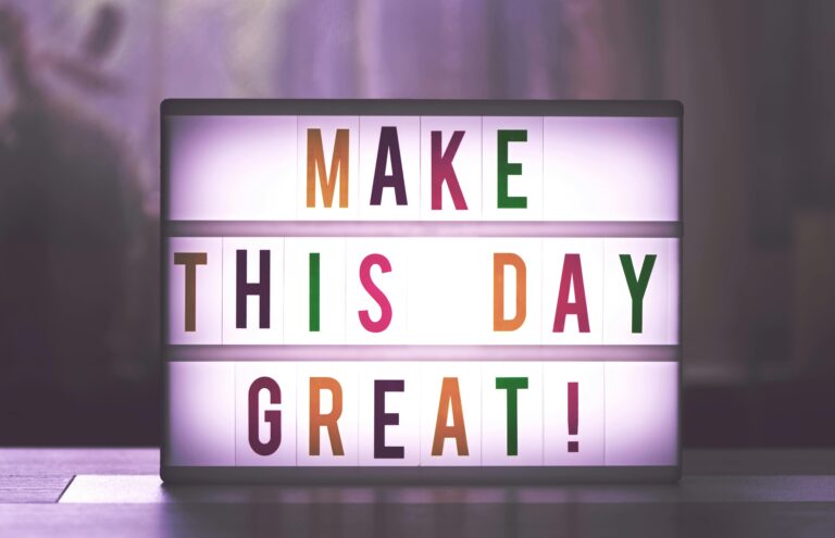 Serenity Body Mind - Image d'article sur la motivation - sur l'image est écrit "make this day great !" en couleurs sur tableau lumineux blanc