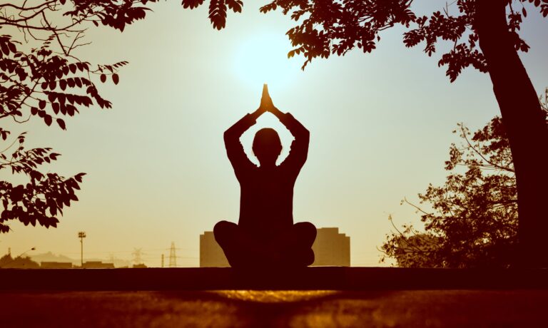 1 personne qui est à la position de lotus à l'exterieur face au soleil. Blog Serenity Body Mind. #SBM #Astuces #meditation
