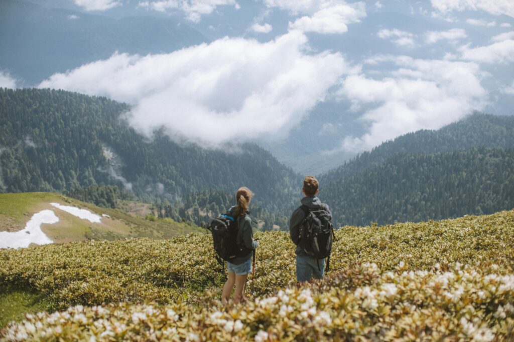 Paysage de montagnes avec herbes vertes et deux personnes regardant vers les montagnes. #SBM #Serenitybodymind